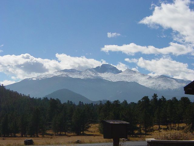 Snapshot of mountains with partial snow cover above evergreen forest