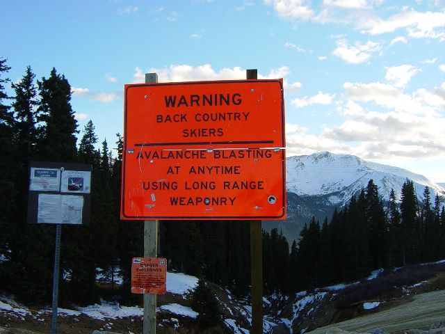 Sign warning back range skiers of long range weaponry used for avalanche blasting