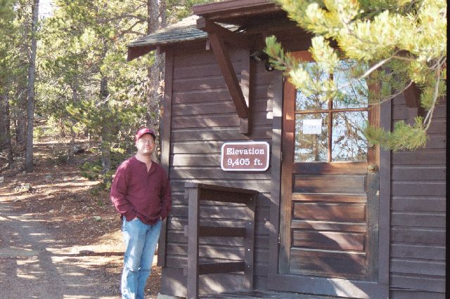 James at rangers station with elvation sign reading 9,405 feet