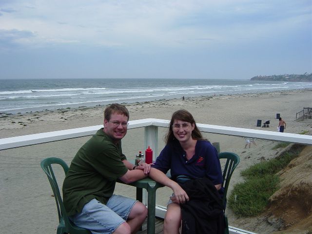 James and Julie at a table with the beach and ocean in the background