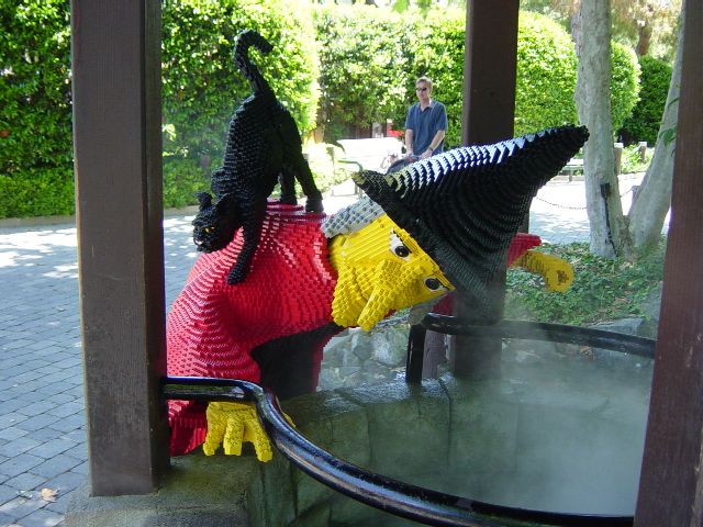 LEGO whitch and black cat look into a steaming well