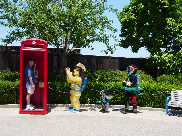 James inside red LEGO callbox from London with line of characters waiting to use the phone
