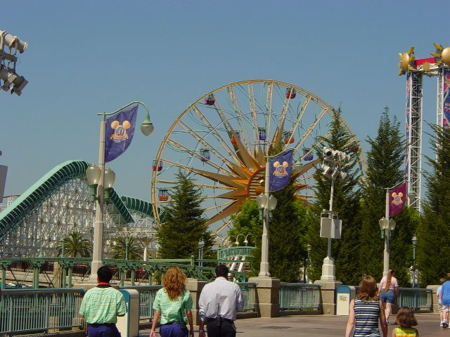 Ferris wheel with Mickey's face in the center in front of a roller coaster