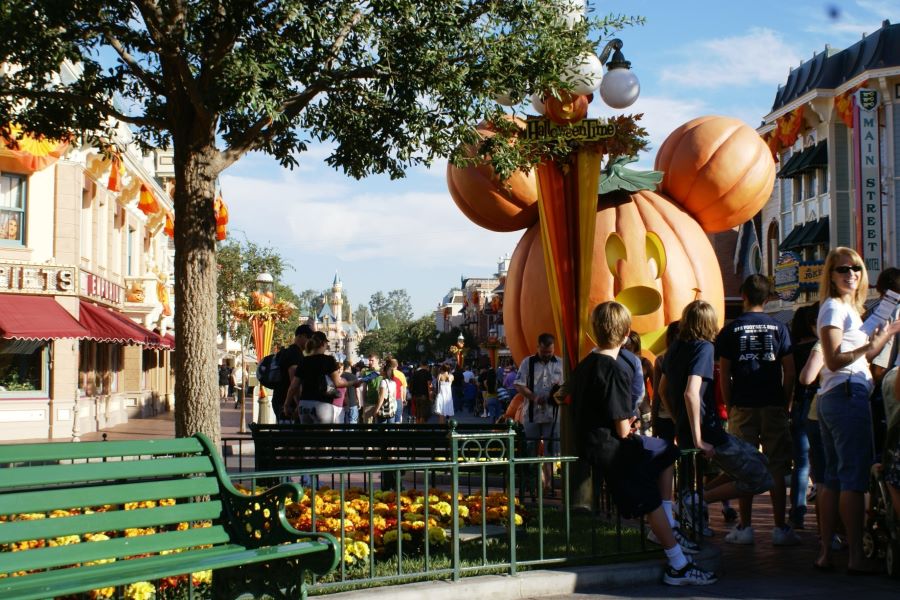 A large pumpkin shaped liked Mickey Mouse's head and ears in front of buildings lining a street