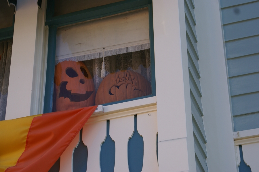 Pumpkins with faces carved into them sitting in a window