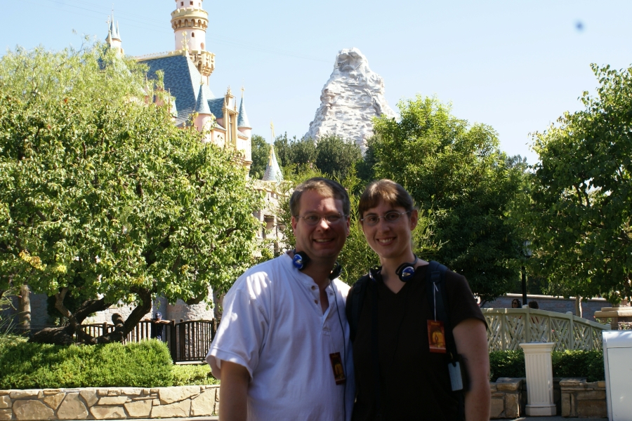 Julie and James stand in the shade of a tree with the Matterhorn ride and Sleeping Beauty’s Castle in the background