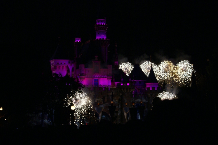 White fireworks surround the castle highlighted with purple lights