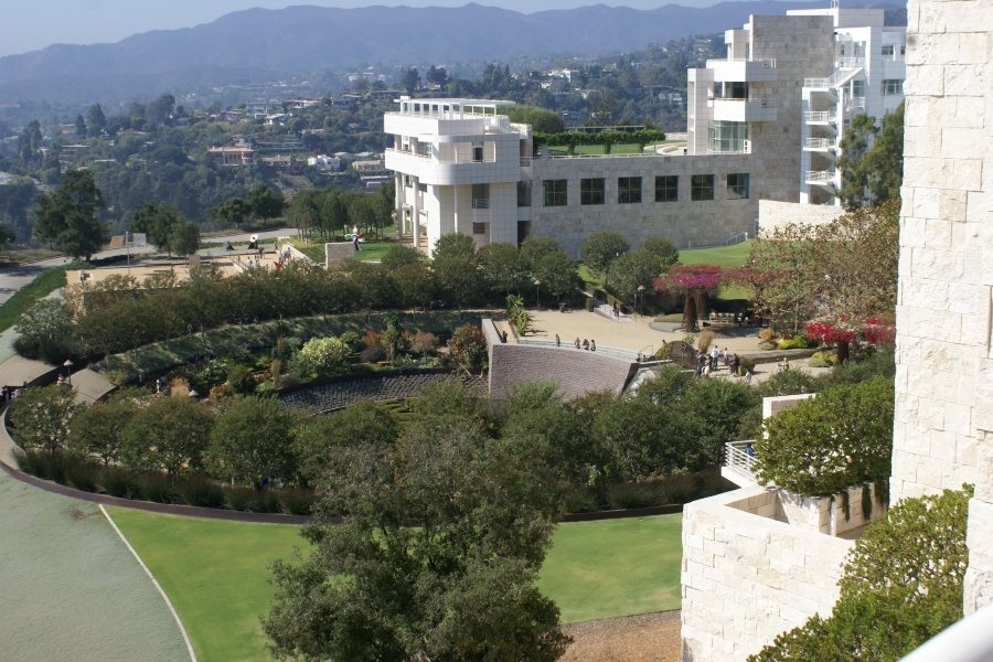 A round garden area is surrounded by white buildings on the side of a hill