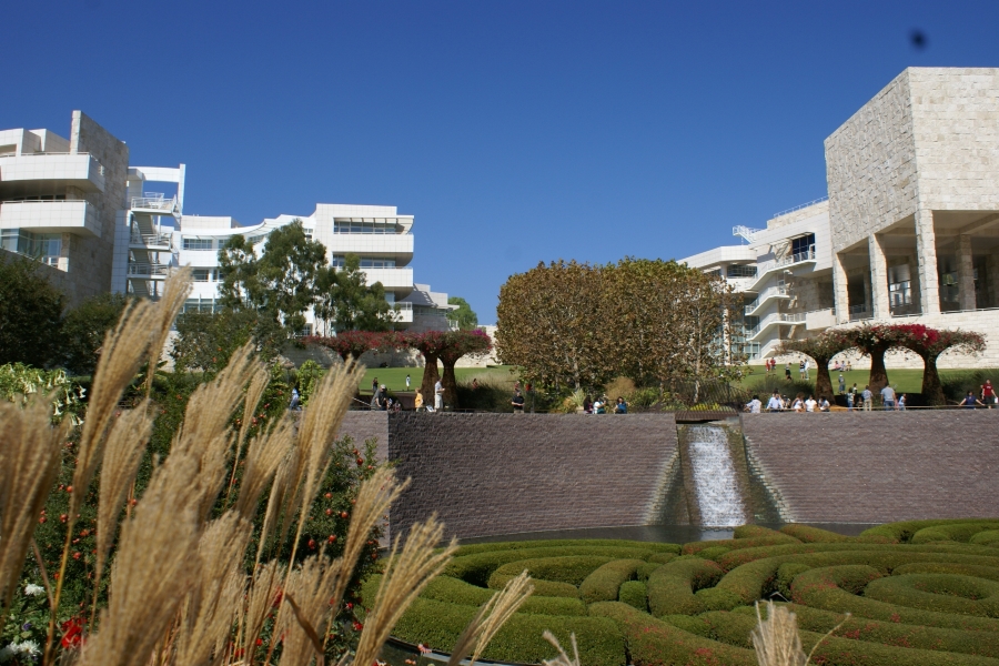 Green shrubs create a maze with white buildings tower above in the distance