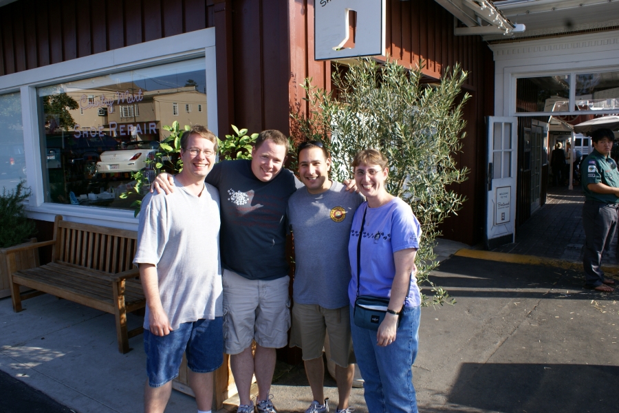 Four people stand in front of a restaurant
