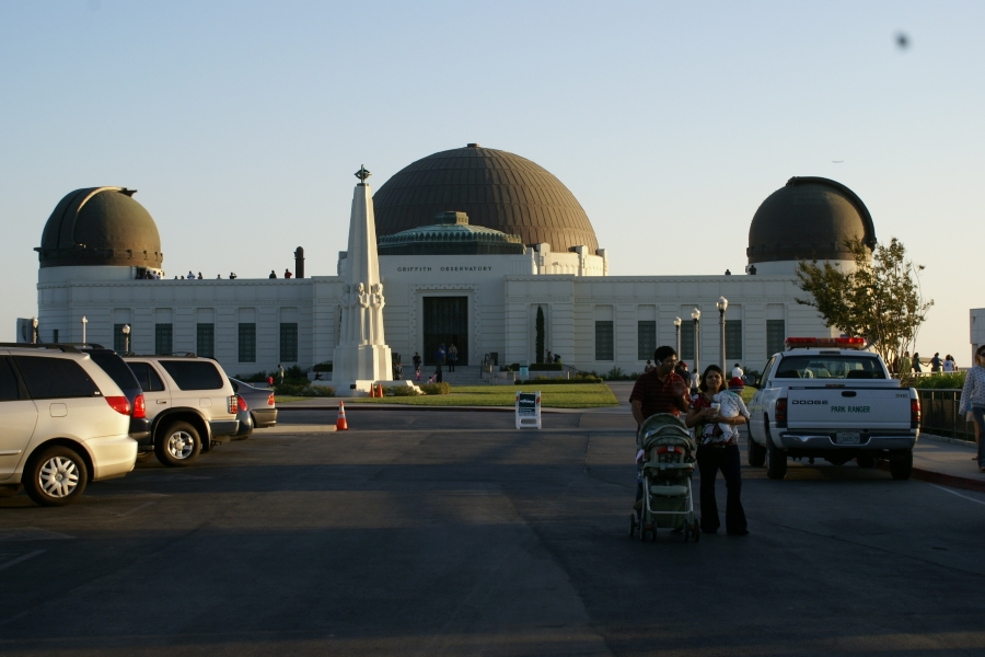 The setting sun shines on a white stone building with bronze domes roofs