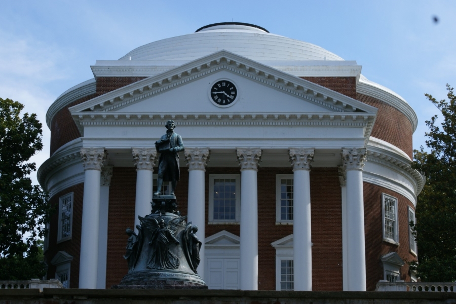 A bronze statue stands in front of a circular brick building with bright white trim and dome