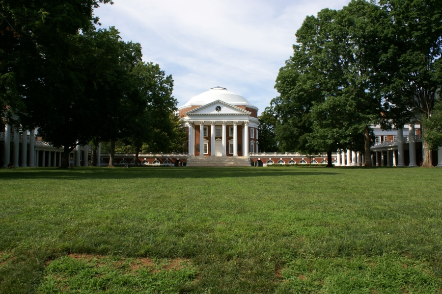 A large rectangular grass open area surrounded by consistent brick with white trim buildings
