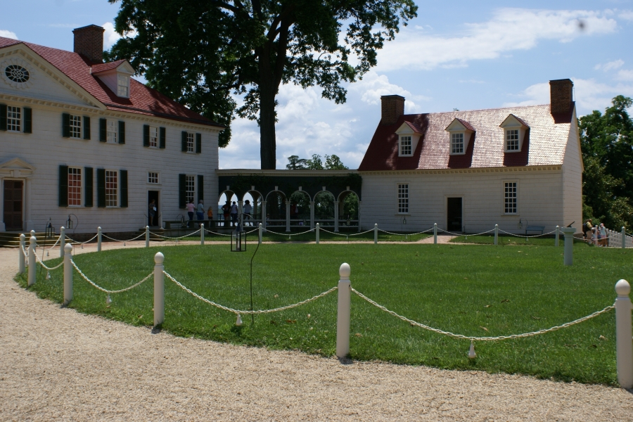 A circular stone drive nestles between two bright white buildings with red roofs and a connecting covered walkway