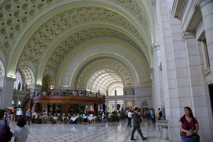 A large concourse filled with people below a white coffered arched ceiling