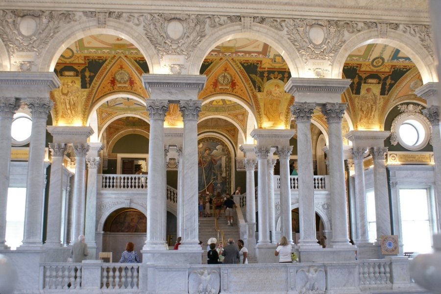 Bright white columns and arches support an arched ceiling with gold and colorful mosaics