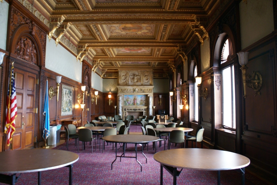 Plush purple carpeting below wooden reading tables in a room with a carved wood ceiling and large windows to one side