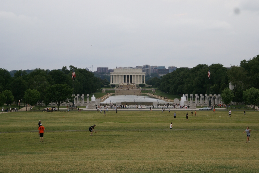 Green grass fields extend to a series of stone arches with a reflecting pool and rectangular white edifice