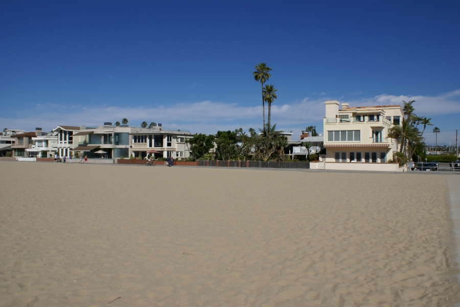Houses with different architectural styles stand side-by-side with only a path separating them from a sandy beach