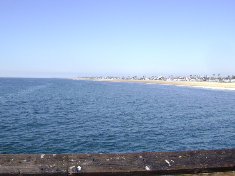 Blue waters run up to a deep sandy beach with houses lining the sand