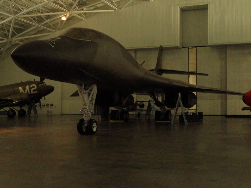 A green plane with swept back wings sits just inside a large hanger door