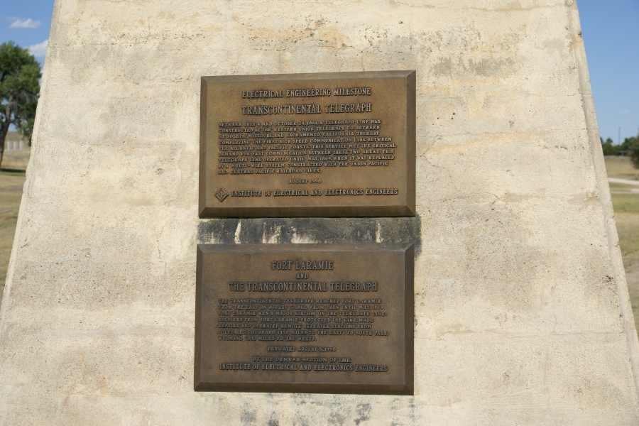 Bronze plaques on a white stone mark the final connection point of the cross-continental telegraph at Fort Laramie, Wyoming