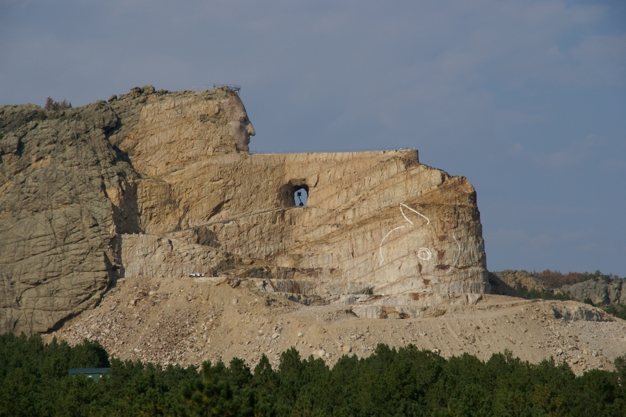 A white stone face looks out over a long flat plane with large amounts of stone rubble below
