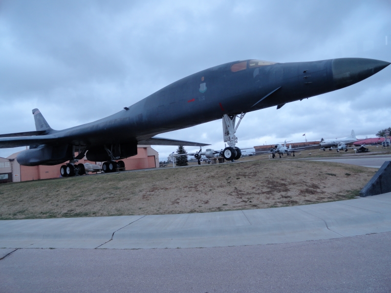 A B-1 bomber sits on a pad in the center of a drive surrounded by several other aircraft
