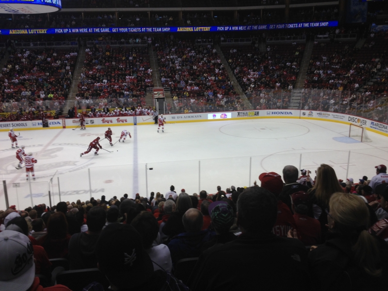A player shoots the puck from near mid ice at an unguarded net