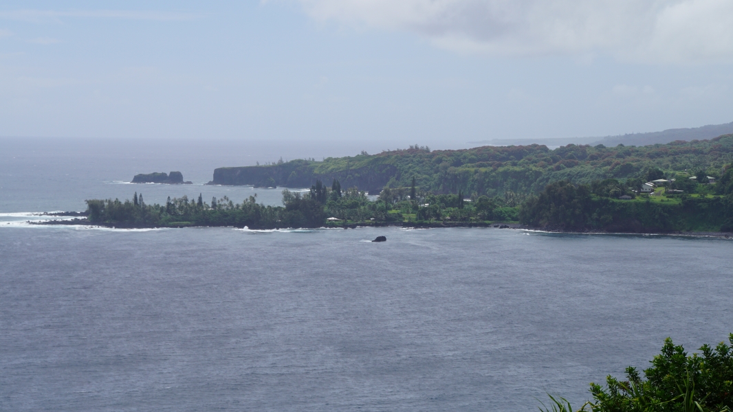 A serene coastal landscape with a vast expanse of blue ocean stretching towards the horizon. A rugged coastline dotted with rocky cliffs and lush greenery extends into the water. Waves crash against the shore, creating a soothing rhythm.