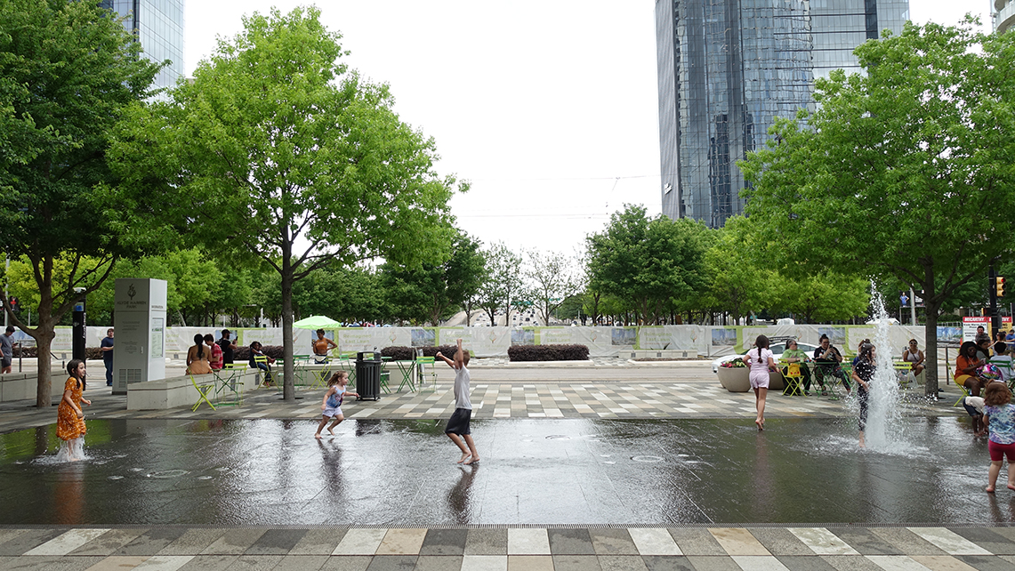 Children play in a flat area with water spouts randomly shooting water into the air