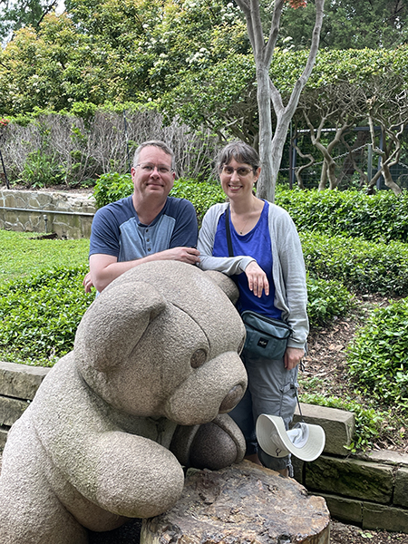 James and Julie standing behind a statue of a teddy bear