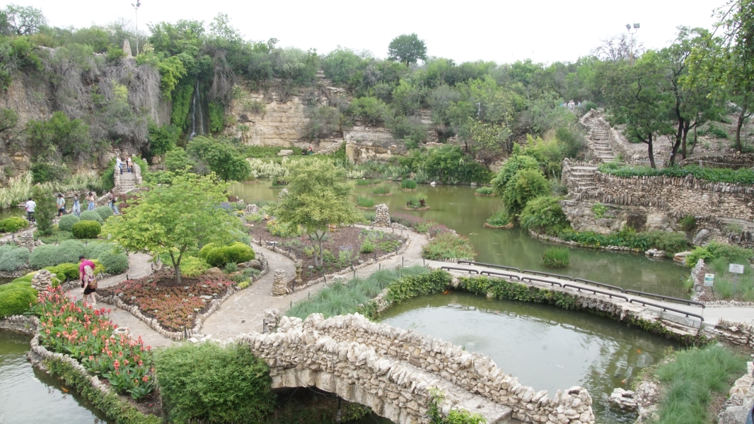 Paths and bridges surrounded by water set in a depressed stone quarry covered with flowers