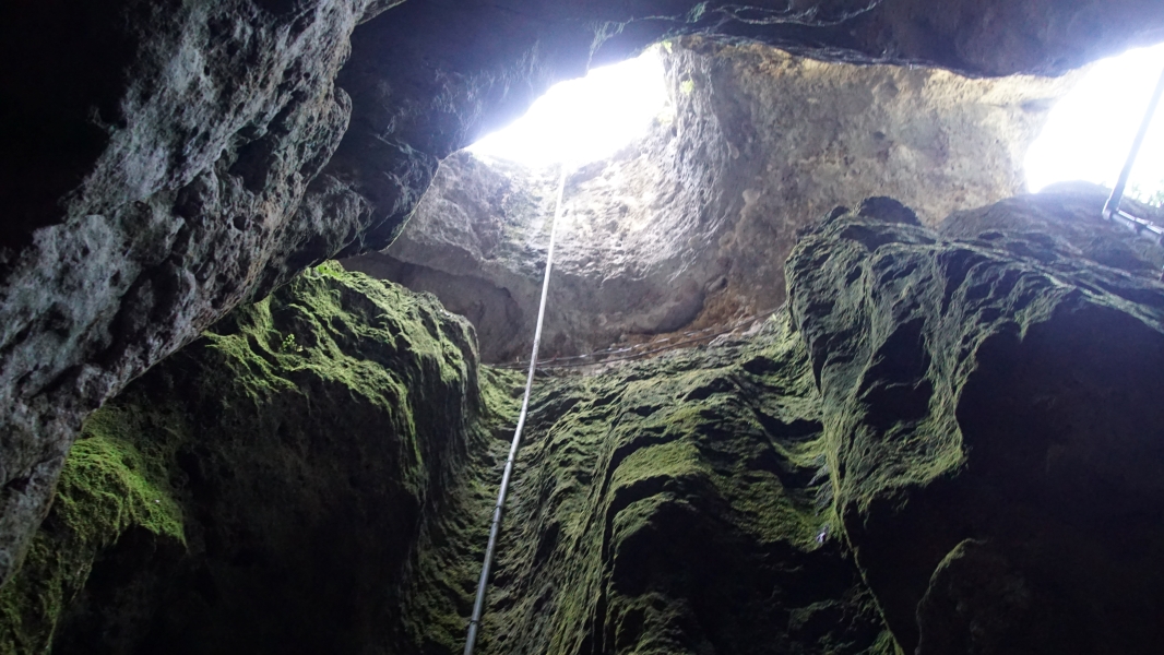 Looking skyward through a vertical shaft of rough stone walls