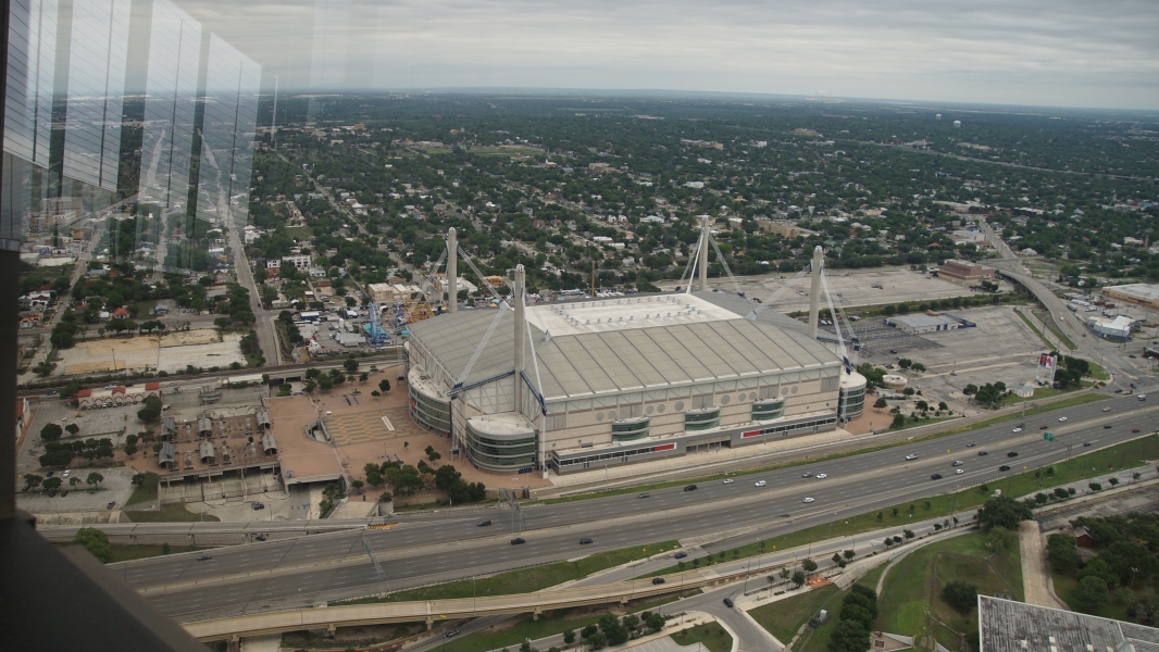 A large building with four spires at the corners stands next to a busy highway