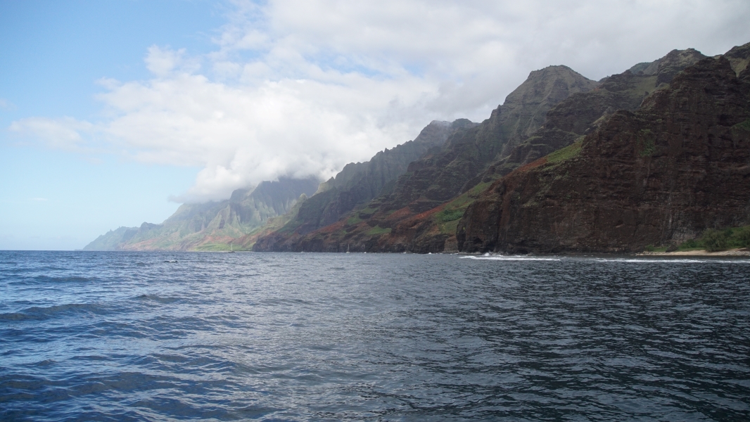 The sun shines down highlighting ridges of towering shear walls creating valleys only accessible from the water