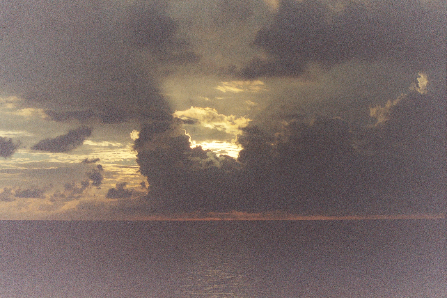 Yellow glow of sunset behind clouds