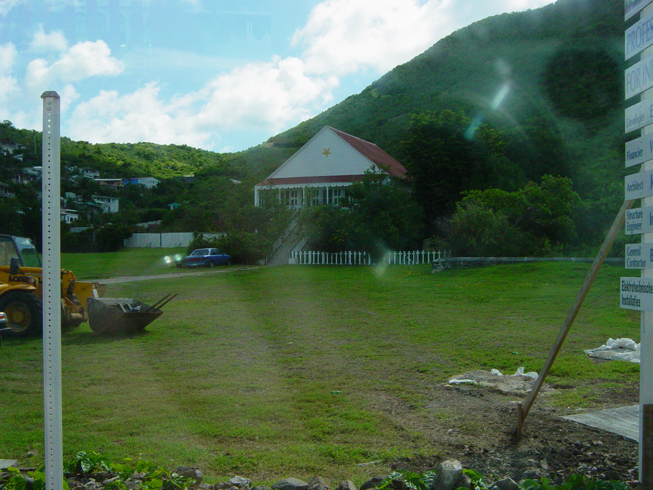 Old house behind trees and a white picket fence