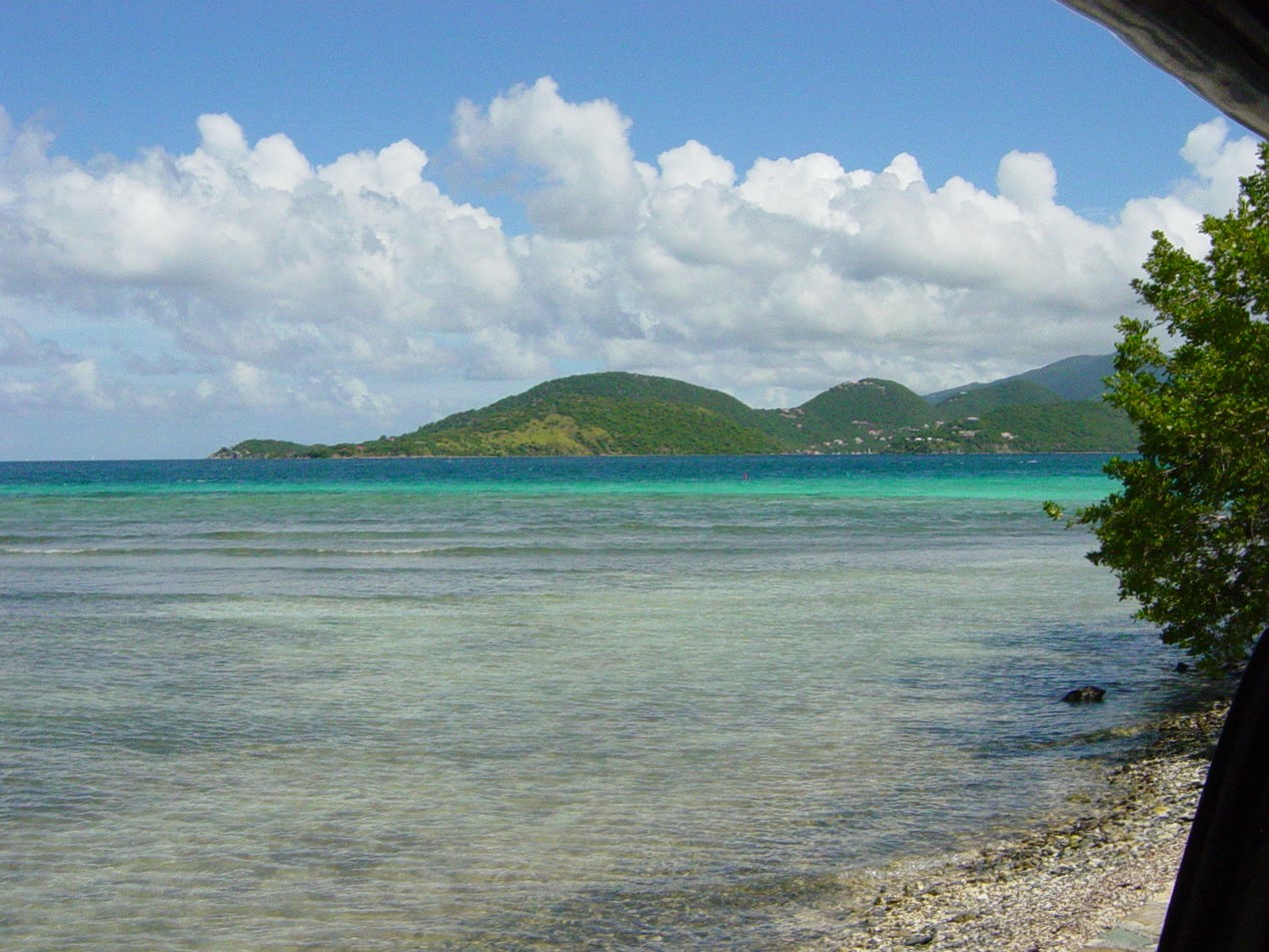 Green hill beyond deep blue waters