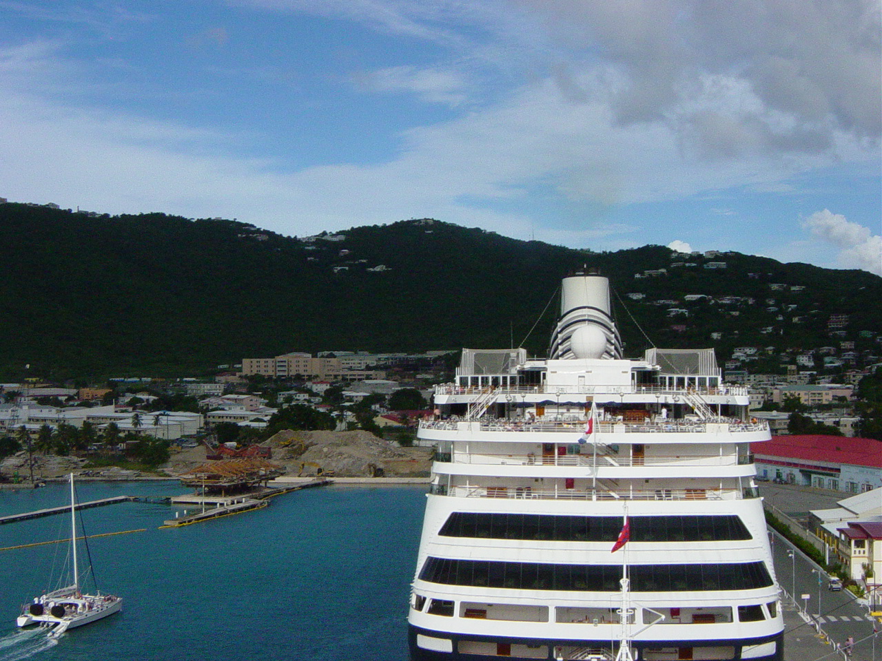 Aft section of large cruise ship with city on hill beyond
