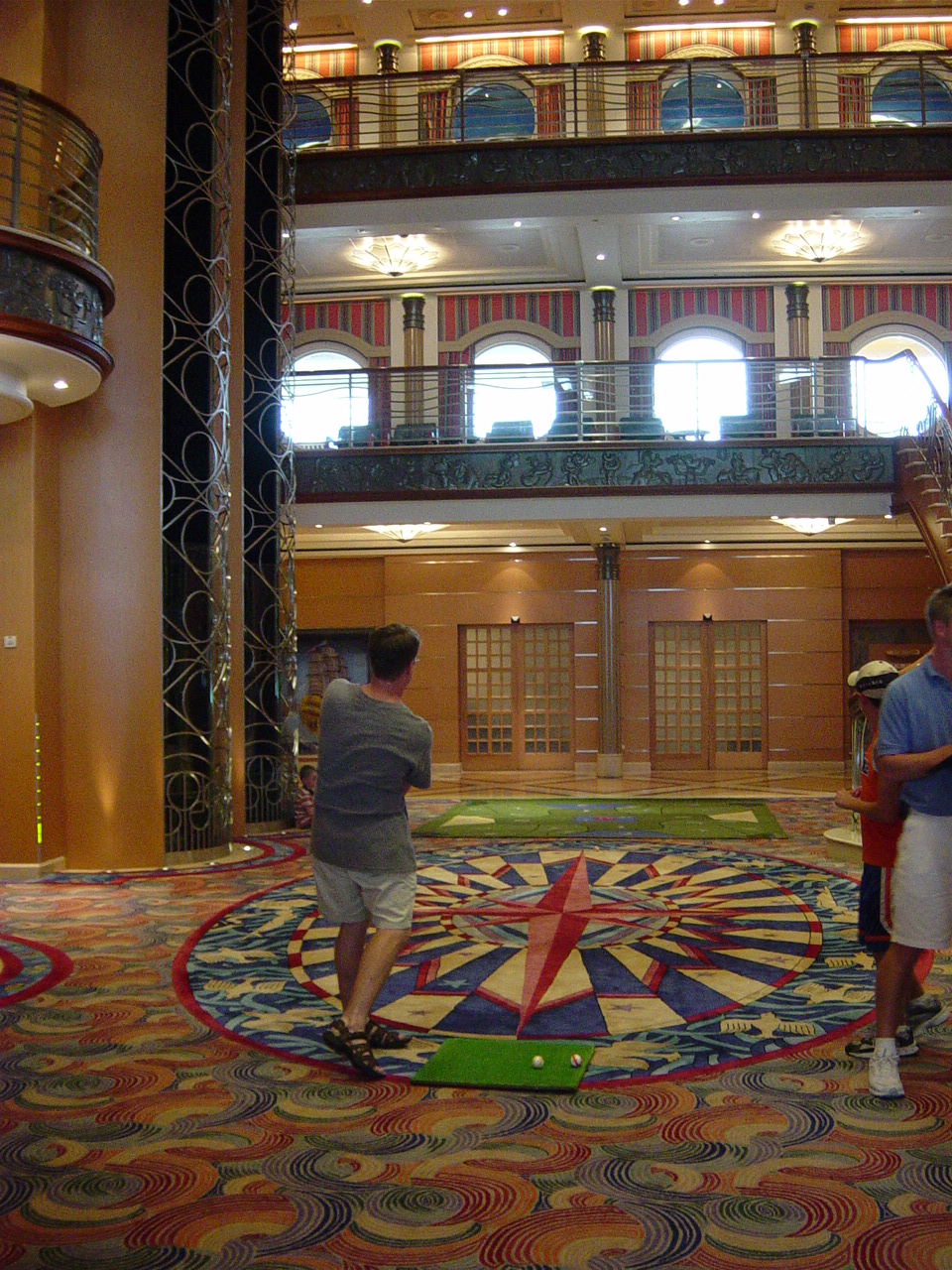 James swinging a wedge golf club in the lobby of the ship