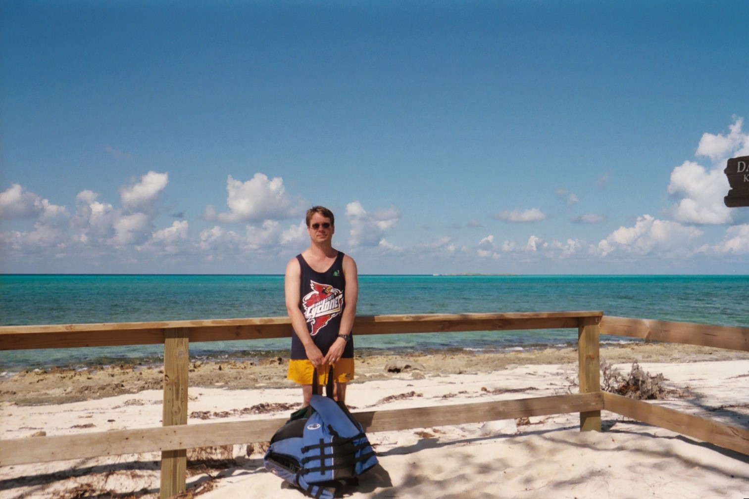James leaning against wood rail fence with ocean in background