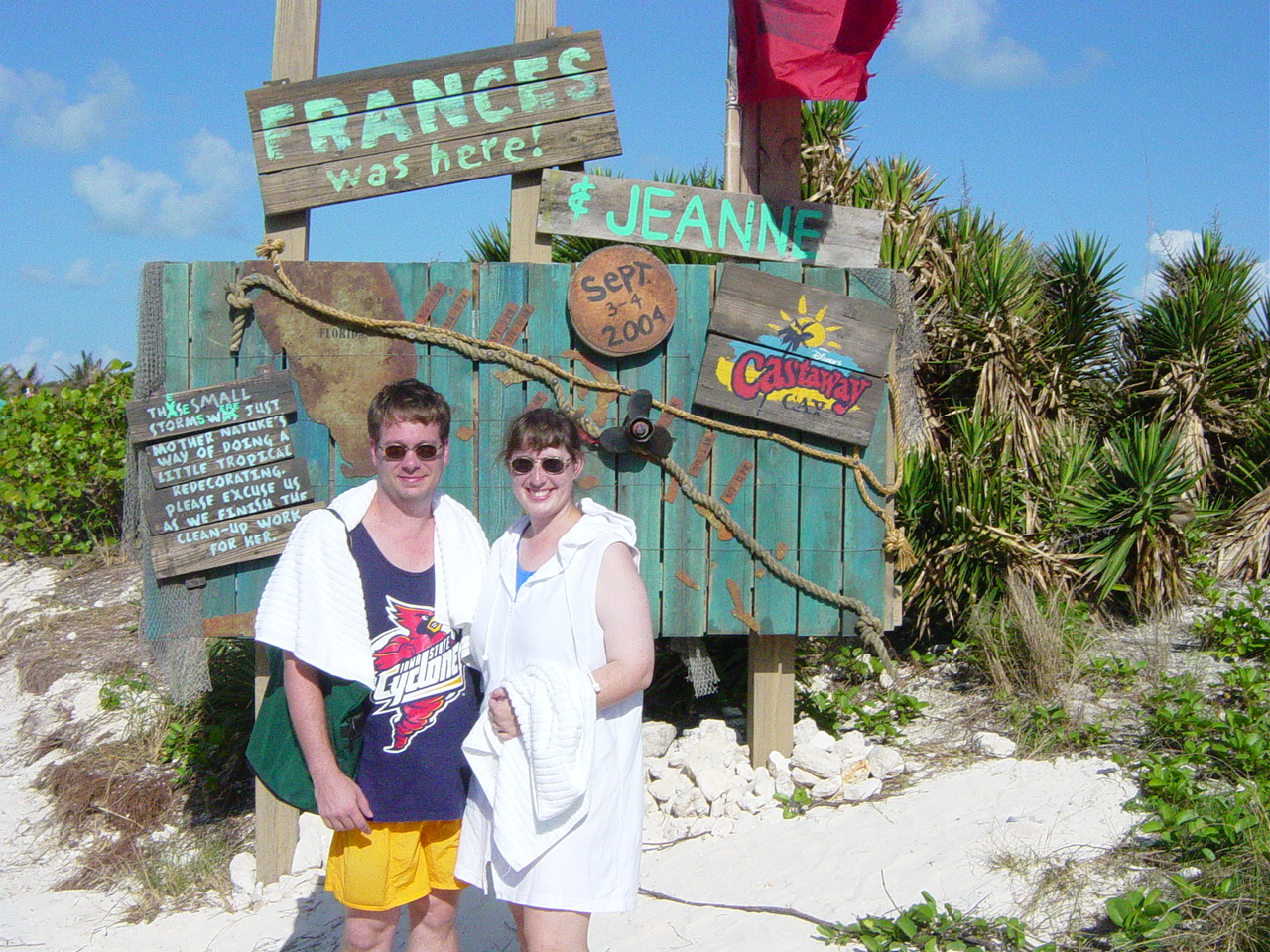 Julie and James in front of sign showing Castaway Cay and the paths of recent hurricanes