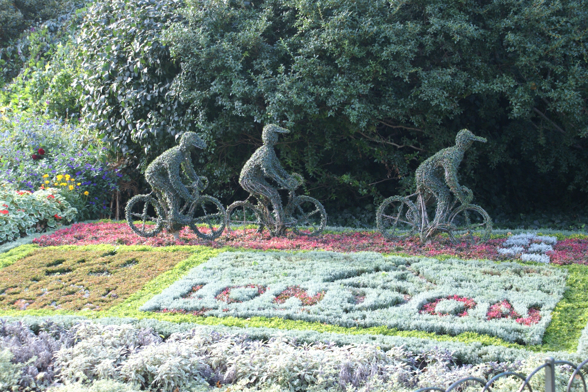 Flower bed with three bicyclist topiaries