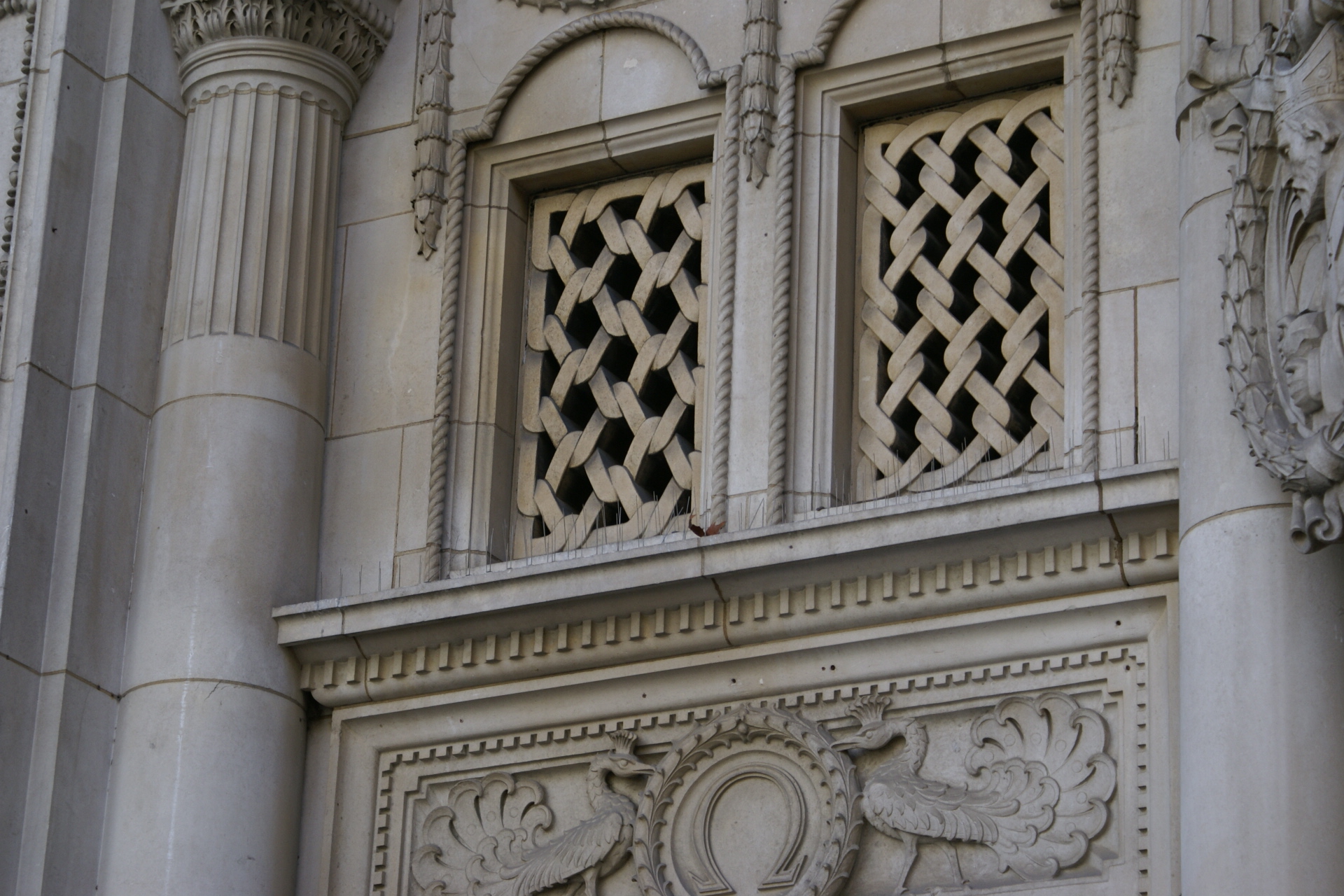 Stonework looking like fence mesh above ornately carved birds