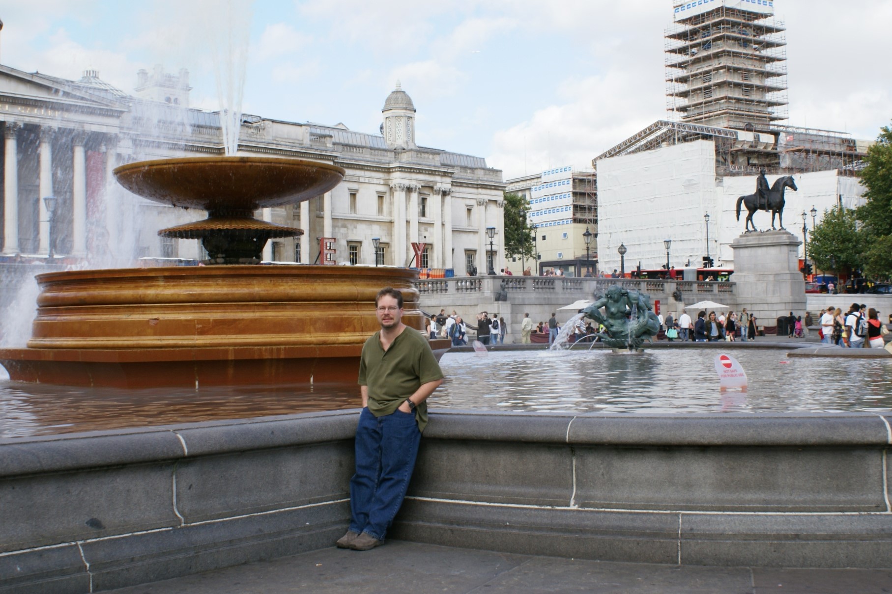 James next to a large fountain in a large public square