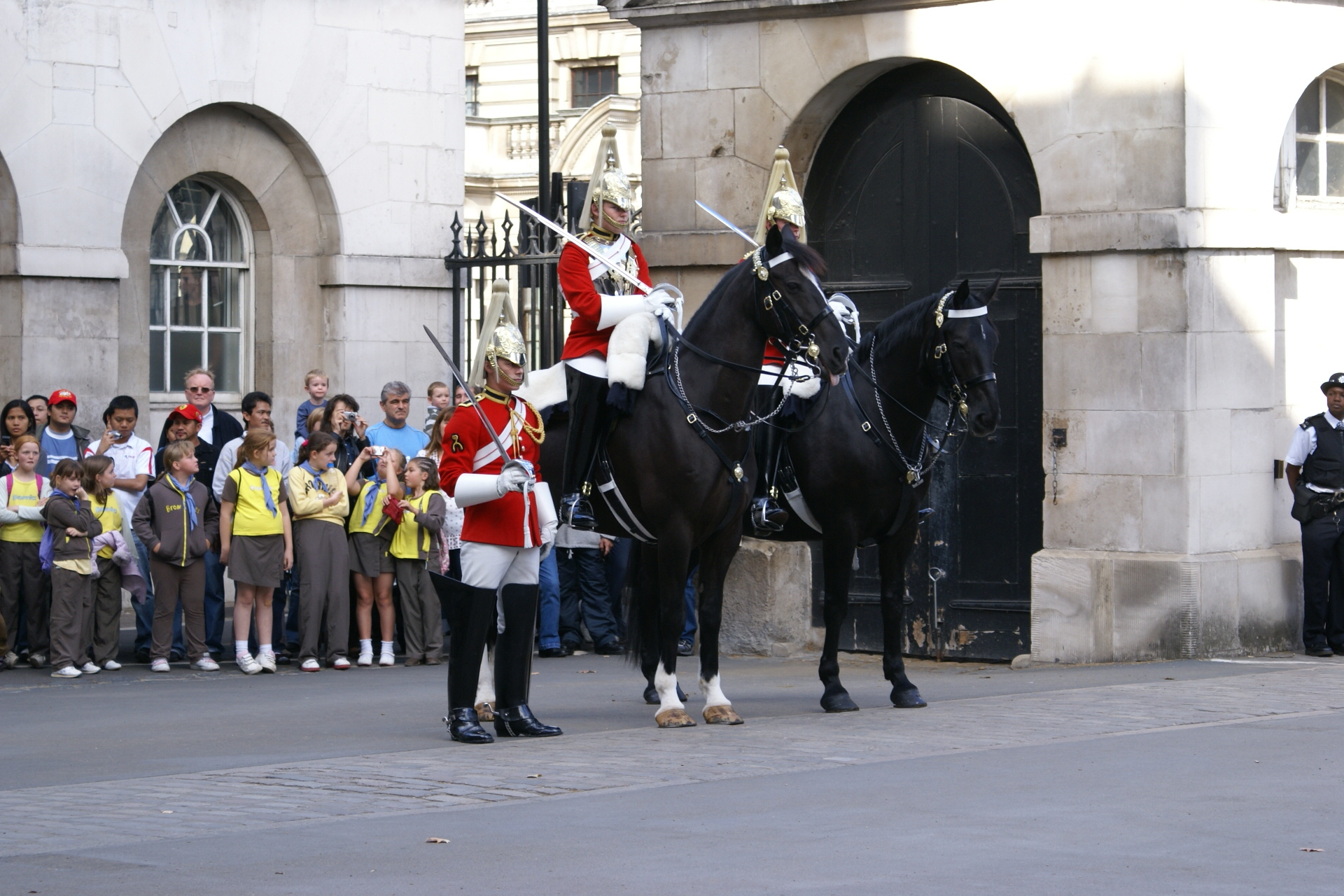Two Royal Guards mounted on black horses with a third standing at attention