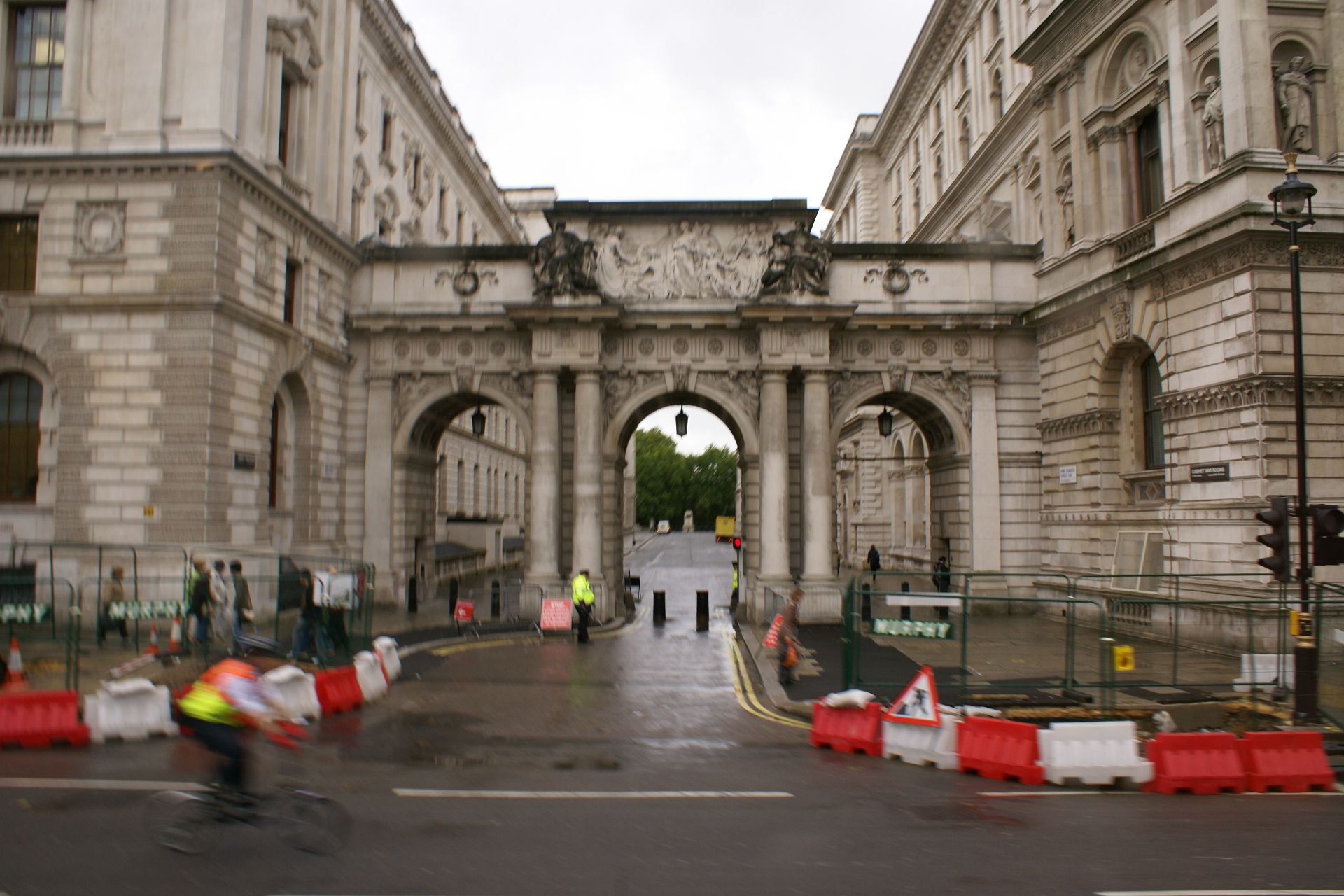 White stone arch between two buildings with police standing at gate
