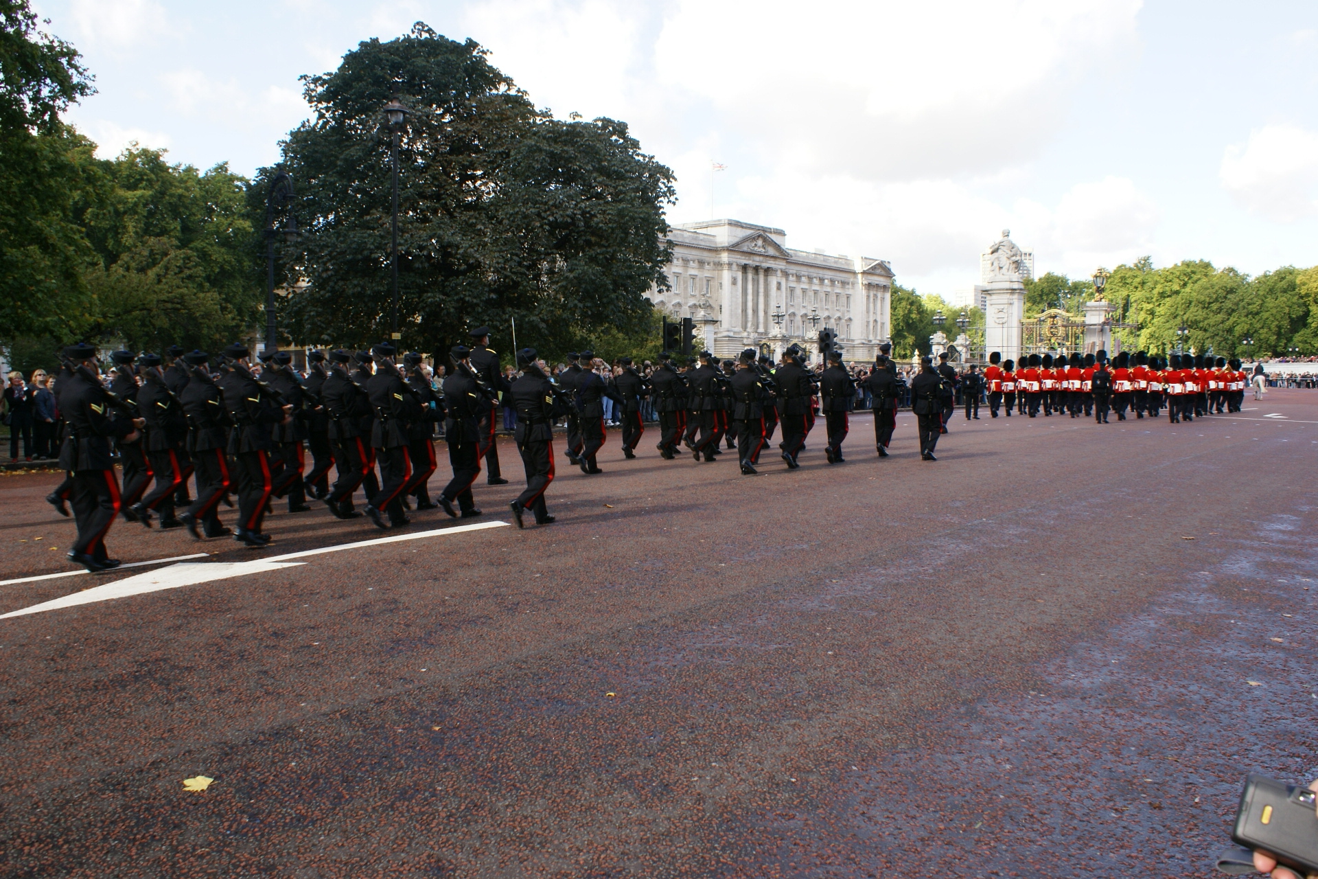 Several lines of men in red and black military uniforms marching down the road