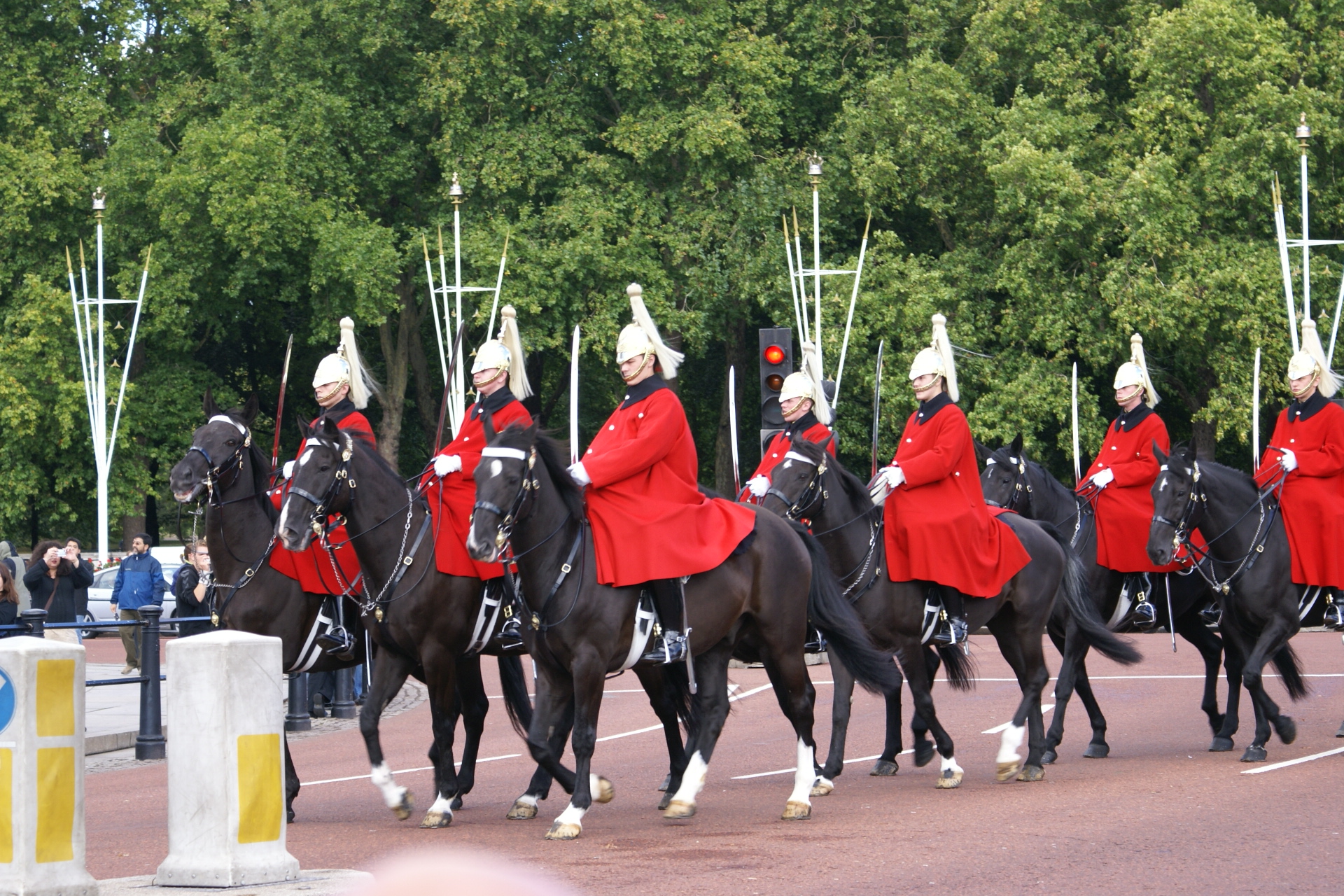 Several mounted guards with large white plumes on their hats riding black horses